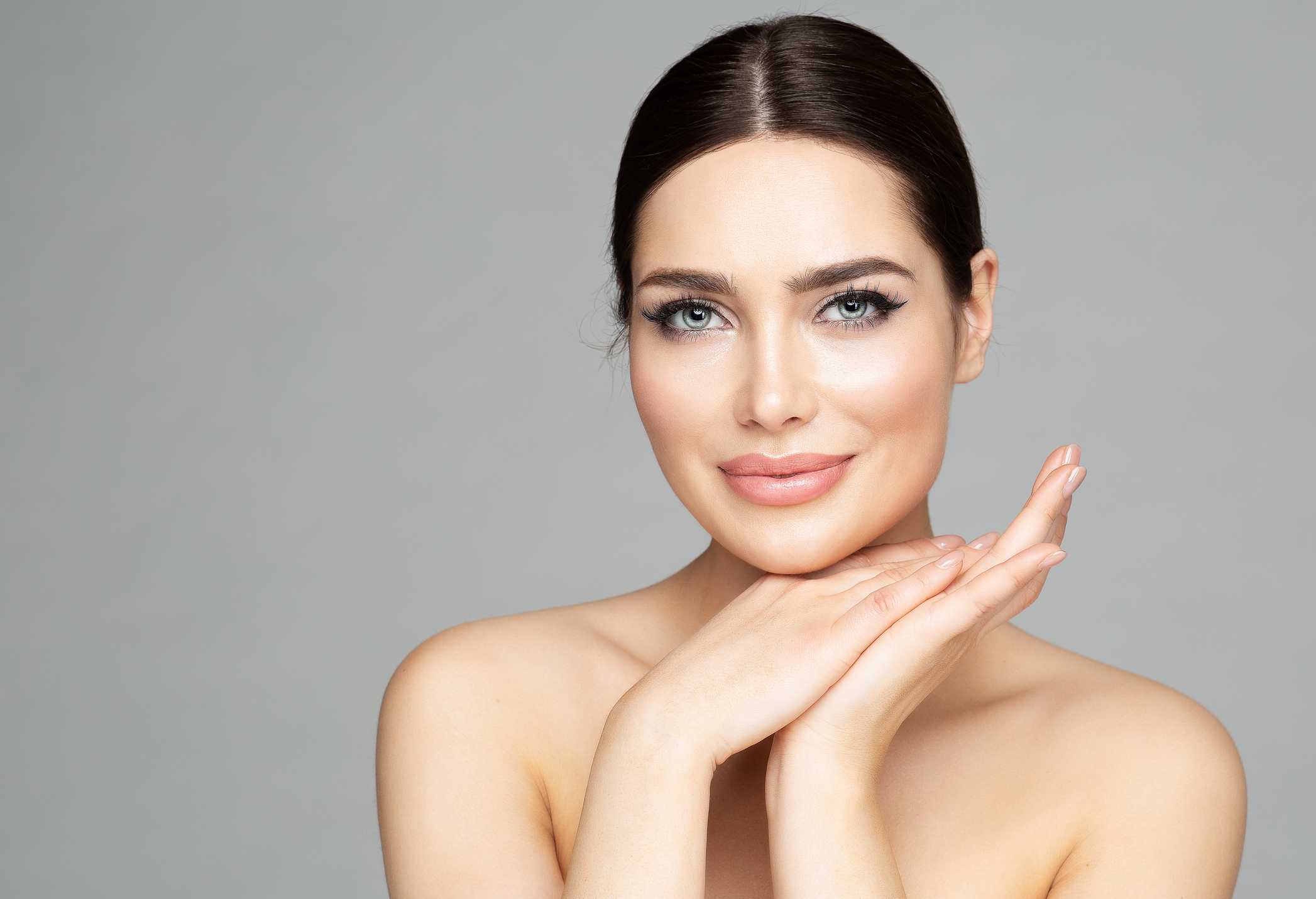 Beauty Woman Face Skin Care. Beautiful Woman Portrait with Full Lips and Long Eyelashes over Gray. Hands Manicure and Facial Treatment Cosmetics. Spa Massage and Face Lift Cosmetology Juvederm Volbella® IN SAN ANTONIO AND BOERNE, TX